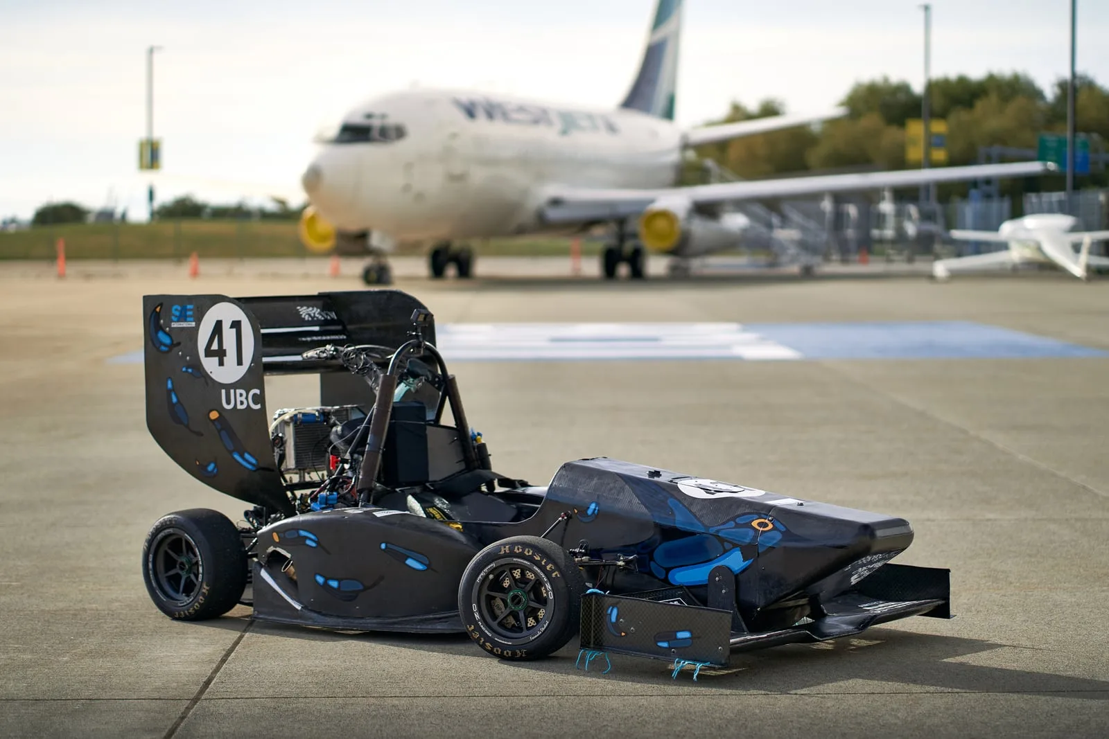 Formula UBC car #41 in front of a WestJet 737